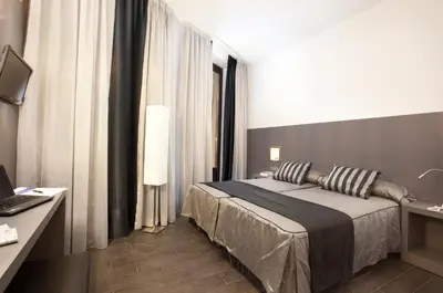a bedroom with a bed and a desk with a laptop at Dalia Ramblas in Barcelona