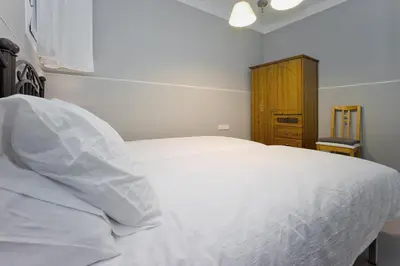 a bedroom with a white bed and a wooden cabinet at Apartamento con Terraza, Balcón de Barcelona in Esplugues de Llobregat