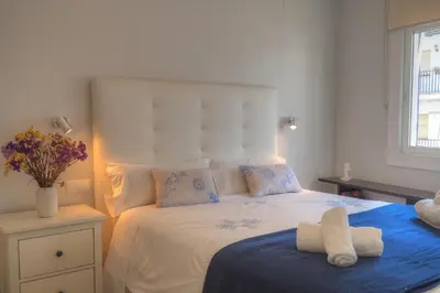 a bedroom with a white bed with a blue blanket at Orquidea Apartment by Hello Homes Sitges in Sitges