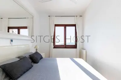 a white bedroom with a bed and a window at Sitges Casa del Mar - Impresionantes vistas al mar in Sitges