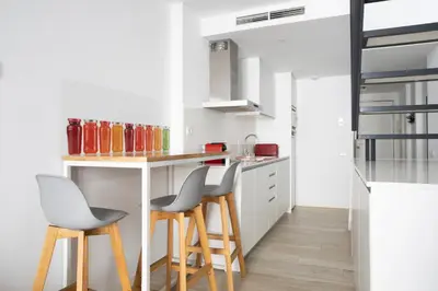 a kitchen with a counter and stools in a room at Urban Suites Sitges Apartments by PriorityVillas in Sitges