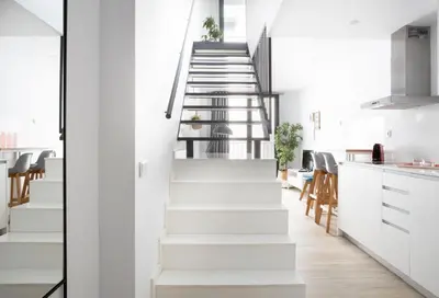 a staircase in a kitchen with white walls and white counters at Urban Suites Sitges Apartments by PriorityVillas in Sitges