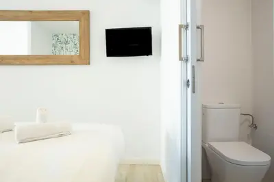 a bathroom with a toilet and a television on the wall at Urban Suites Sitges Apartments by PriorityVillas in Sitges