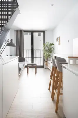 a kitchen and living room with white cabinets and chairs at Urban Suites Sitges Apartments by PriorityVillas in Sitges