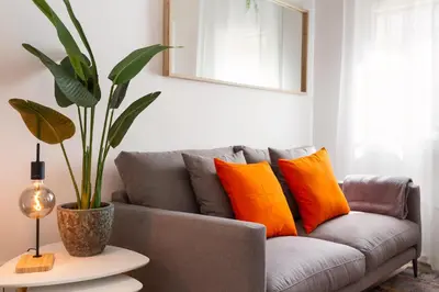 a gray couch with orange pillows in a living room at Confort apartamentos en playa, 3 DRM in Barcelona