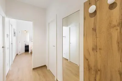 a hallway with white walls and wood floors and a mirror at Confort apartamentos en playa, 3 DRM in Barcelona