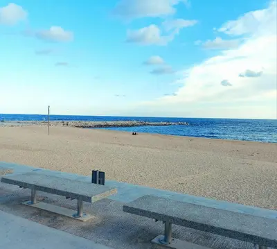 two benches sitting on the beach near the ocean at Confort apartamentos en playa, 3 DRM in Barcelona