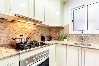 a kitchen with white cabinets and a pot on the stove at Click&Flat Fira Gran Via in Hospitalet de Llobregat