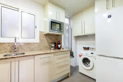 a kitchen with white cabinets and a washer and dryer at Click&Flat Fira Gran Via in Hospitalet de Llobregat