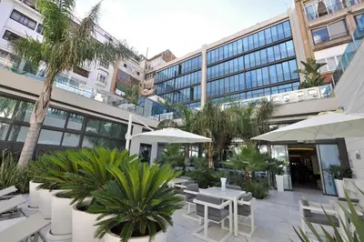 a patio with tables and umbrellas in front of a building at Hotel Indigo Barcelona - Plaza Catalunya 4Sup by IHG in Barcelona