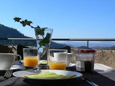 a table with a plate of food and glasses of orange juice at Can Seuba in Rellinars