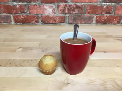 a red cup of coffee and a muffin on a table at Practical room: Barcelona-Fira-Airport in Hospitalet de Llobregat
