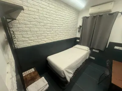 a small room with a small bed and a brick wall at Practical room: Barcelona-Fira-Airport in Hospitalet de Llobregat