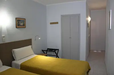 a hotel room with two beds and a chair at Hotel Alexandra Sitges in Sitges