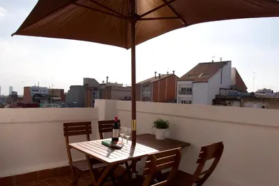 a table with a bottle of wine and an umbrella on a balcony at Sant Pau Terraces Apartments in Barcelona