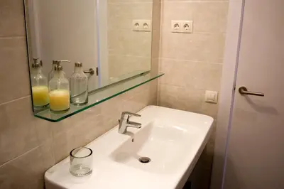 a bathroom with a sink and a mirror and glass bottles at Sant Pau Terraces Apartments in Barcelona