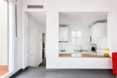 a kitchen with white cabinets and a red couch at Sant Pau Terraces Apartments in Barcelona