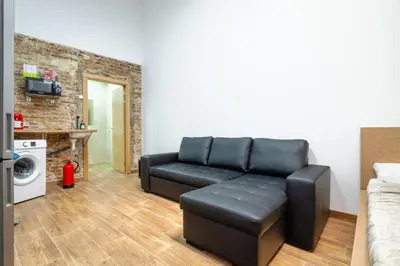 a living room with a black leather couch at CAMP NOU & FiRA BUSINESS LOFTS in Barcelona