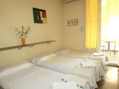 a room with three beds and a table at Hostal Lima in Barcelona