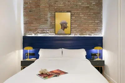 a bedroom with a white bed and a brick wall at Arte Suites by Olala! - Smart Stay in Hospitalet de Llobregat