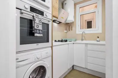 a white kitchen with a washing machine and a sink at Quiet, Ultra-Central Stay KM0 for 3 in Barcelona