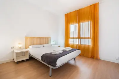 a bedroom with a bed and a window with orange curtains at Quiet, Ultra-Central Stay KM0 for 3 in Barcelona