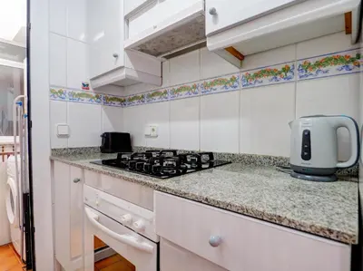 a kitchen with white cabinets and a stove top oven at Amazing Seaview Apartment by Hello Homes Sitges in Sitges