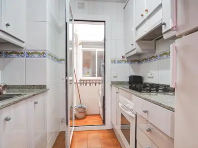 a kitchen with white cabinets and a glass door at Amazing Seaview Apartment by Hello Homes Sitges in Sitges