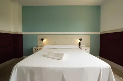 a bedroom with a white bed with blue walls at Hotel Consentido in Granollers