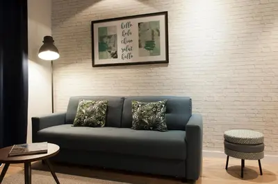 a blue couch in a living room with a brick wall at MH Apartments Sant Pau in Barcelona