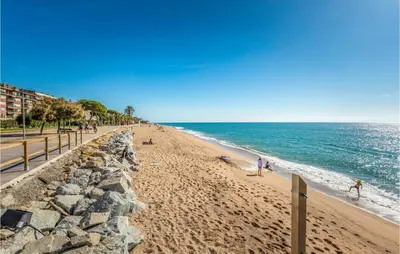 a beach with people on the sand and the ocean at Stunning Apartment In Pineda De Mar in Pineda de Mar