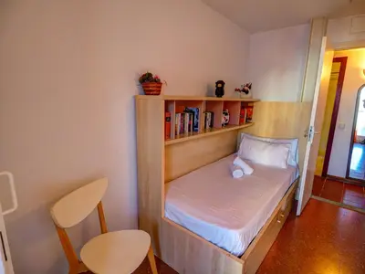 a small room with a bed with a book shelf at Aquamarine Terrace Apartment by Hello Homes Sitges in Sitges