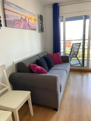 a living room with a gray couch with red pillows at Beach Apartment in Vilanova i la Geltrú