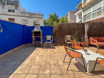a patio with chairs and a grill on a blue wall at The Beach House Paradise by Hello Homes Sitges in Sitges