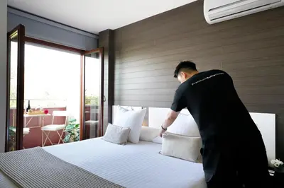 a man making a bed in a hotel room at Abarco Apartments in Santa Coloma