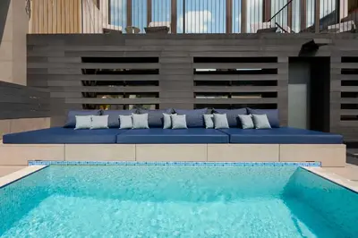 a swimming pool with blue cushions next to a building at Catalonia Gran Via BCN in Barcelona