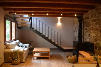 a living room with a staircase and a couch at Cal Puó Turismo Rural in Collsuspina