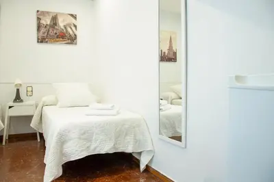 a white bedroom with a bed and a mirror at Barcelona City Street Hostal in Barcelona