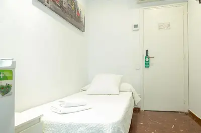 a white room with a bed and a mirror at Barcelona City Street Hostal in Barcelona