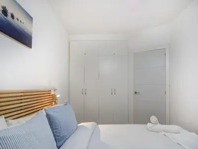a white bedroom with a bed and a closet at White Center Apartment by Hello Homes Sitges in Sitges