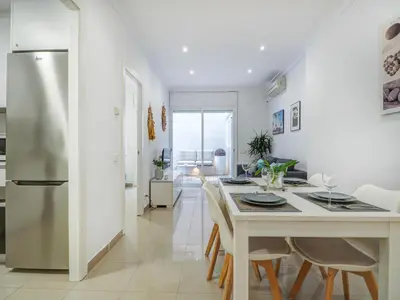 a kitchen and dining room with a table and chairs at White Center Apartment by Hello Homes Sitges in Sitges