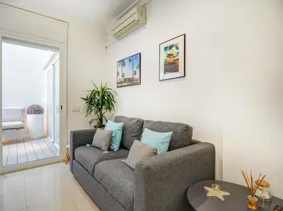 a living room with a couch and a window at White Center Apartment by Hello Homes Sitges in Sitges