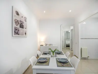 a white dining room with a table and white chairs at White Center Apartment by Hello Homes Sitges in Sitges