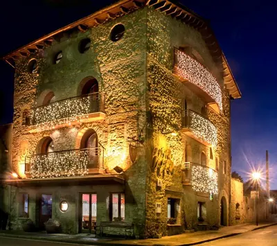 a building with christmas lights on the side of it at La Violeta HOTEL SPA & CHILL OUT in Castelltersol