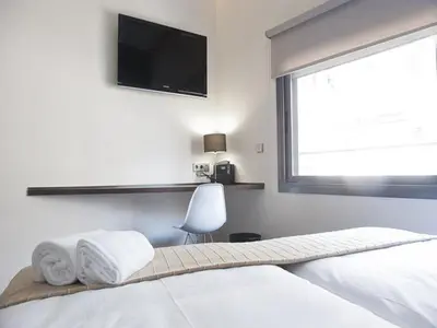 a bedroom with a bed with a television on the wall at Barcelona Fifteen central Aparthotel in Barcelona