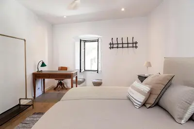 a white bedroom with a bed and a desk at A historic XVI century beach home near Barcelona in Caldes d'Estrac