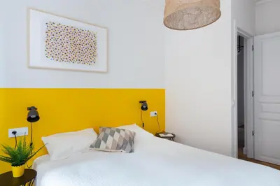 a bedroom with a white bed and a yellow wall at Casa Cosi - Francoli 1 in Barcelona