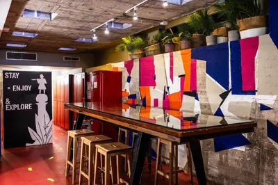 a room with a table with stools and a colorful wall at Urbany Hostel BCN GO! in Barcelona