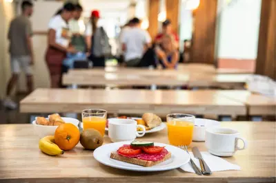 a table with a plate of breakfast foods and orange juice at Urbany Hostel BCN GO! in Barcelona