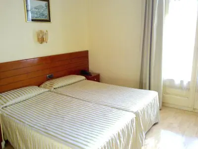 a bedroom with a bed with a wooden headboard and a window at Hotel Toledano Ramblas in Barcelona